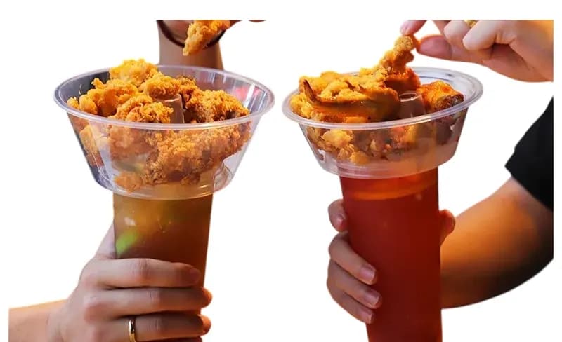 Two hands holding Cupify sets: fried chicken in the clear bowls, iced drinks in the cups